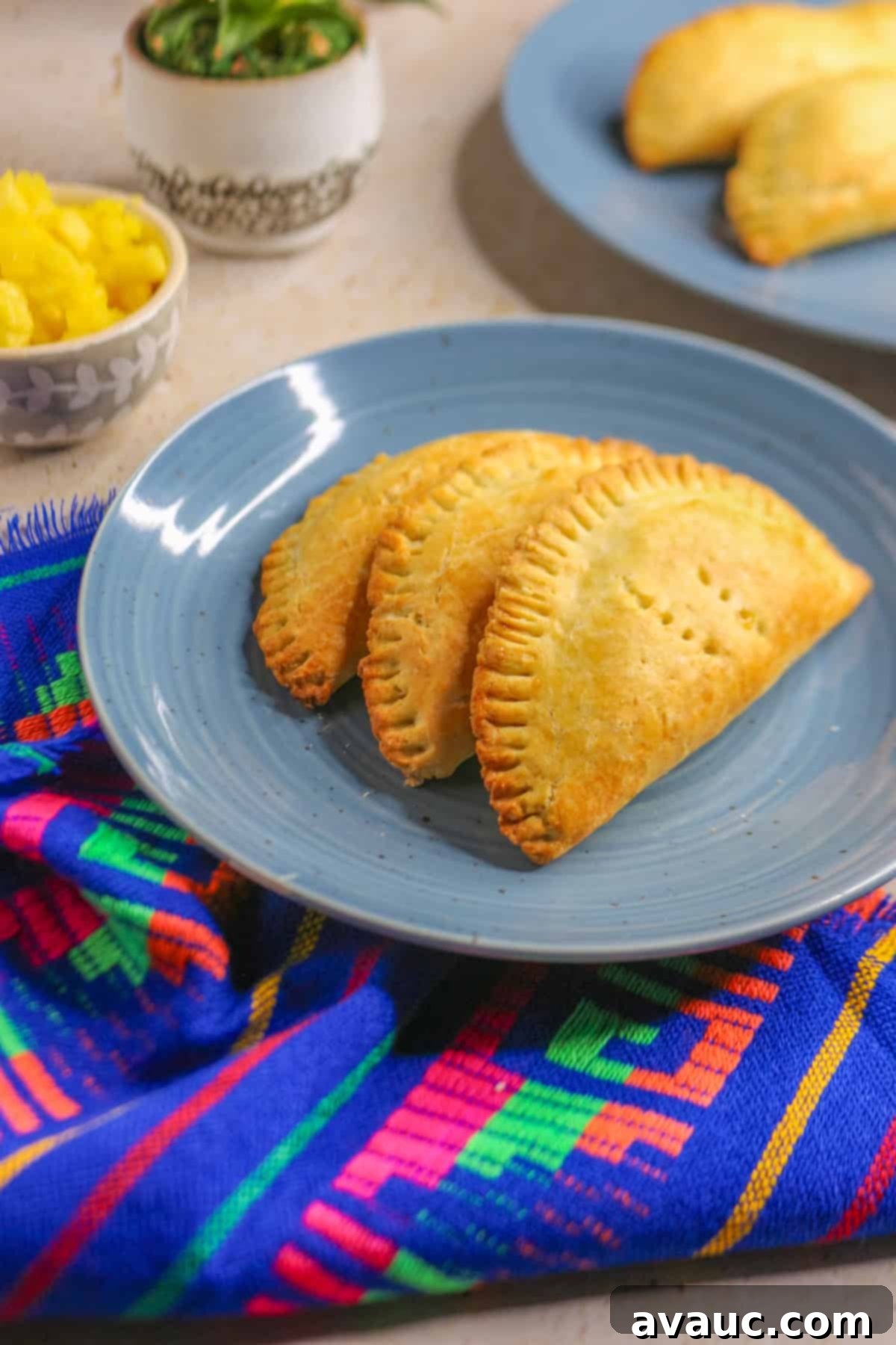 Delightful Gluten-Free Pineapple Empanadas 2 Freshly baked Gluten-Free Empanadas de Piña on a white plate, garnished with powdered sugar