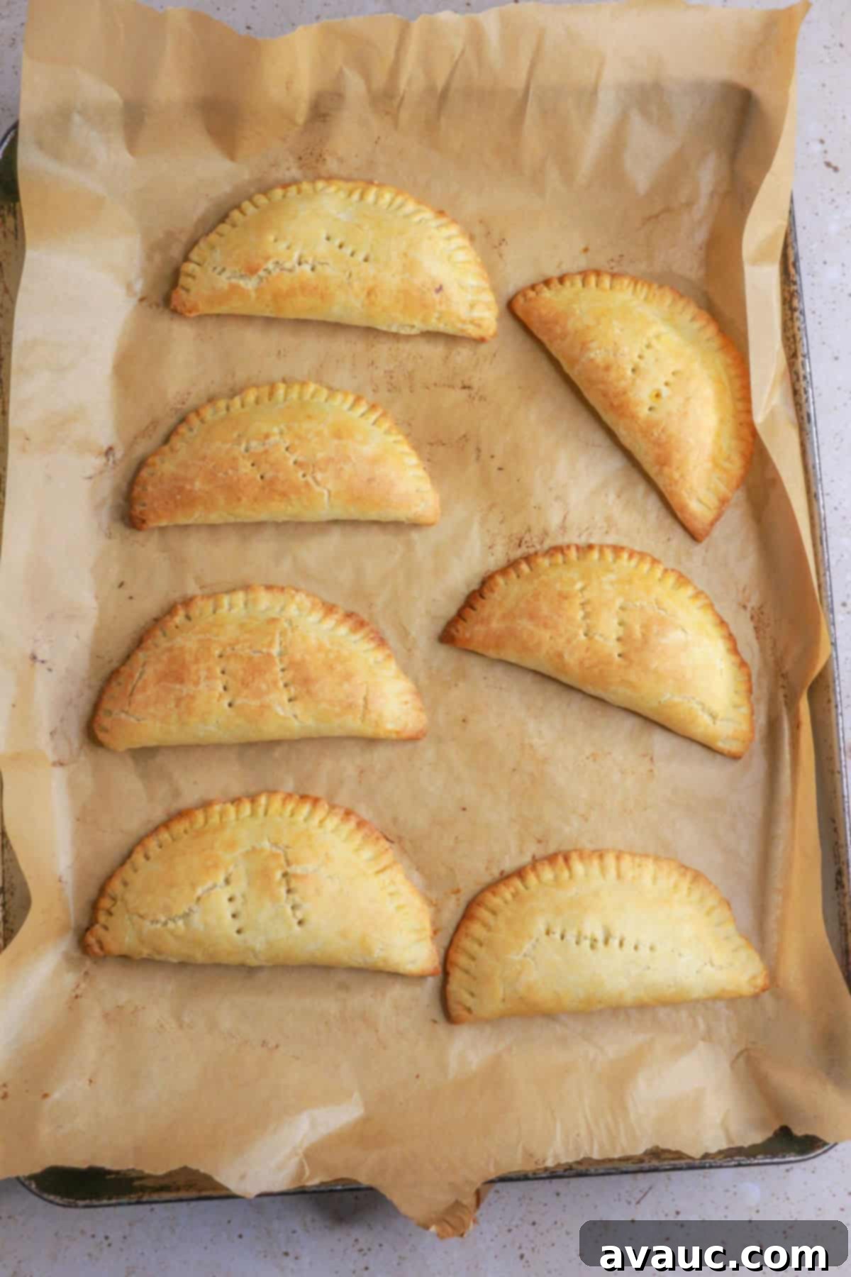 Delightful Gluten-Free Pineapple Empanadas 14 Baked empanadas on a baking sheet, golden brown and ready to serve
