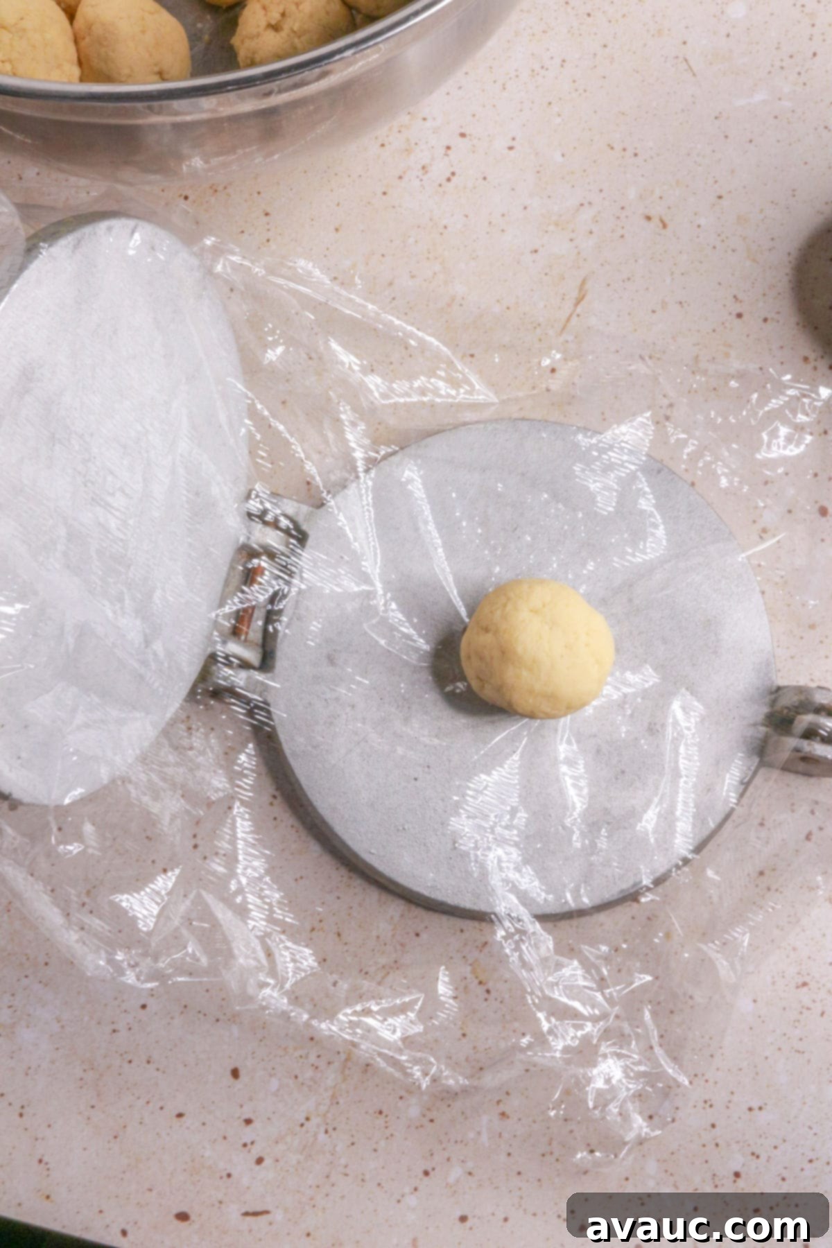 Delightful Gluten-Free Pineapple Empanadas 10 Dough ball on a tortilla press lined with plastic wrap