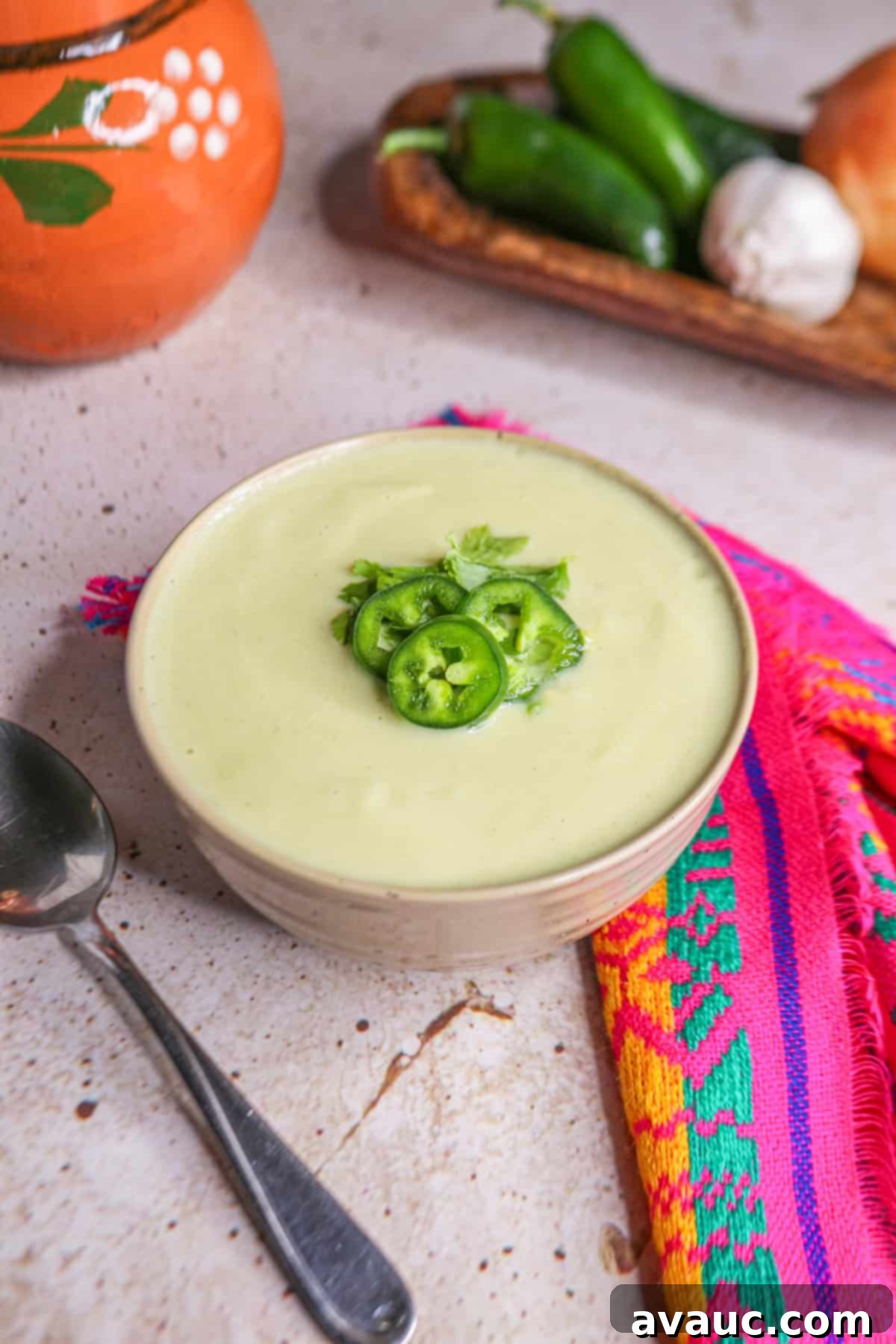 Cream of Onion Soup with Jalapeño in a small bowl topped with jalapeño slices, garnished with fresh cilantro.