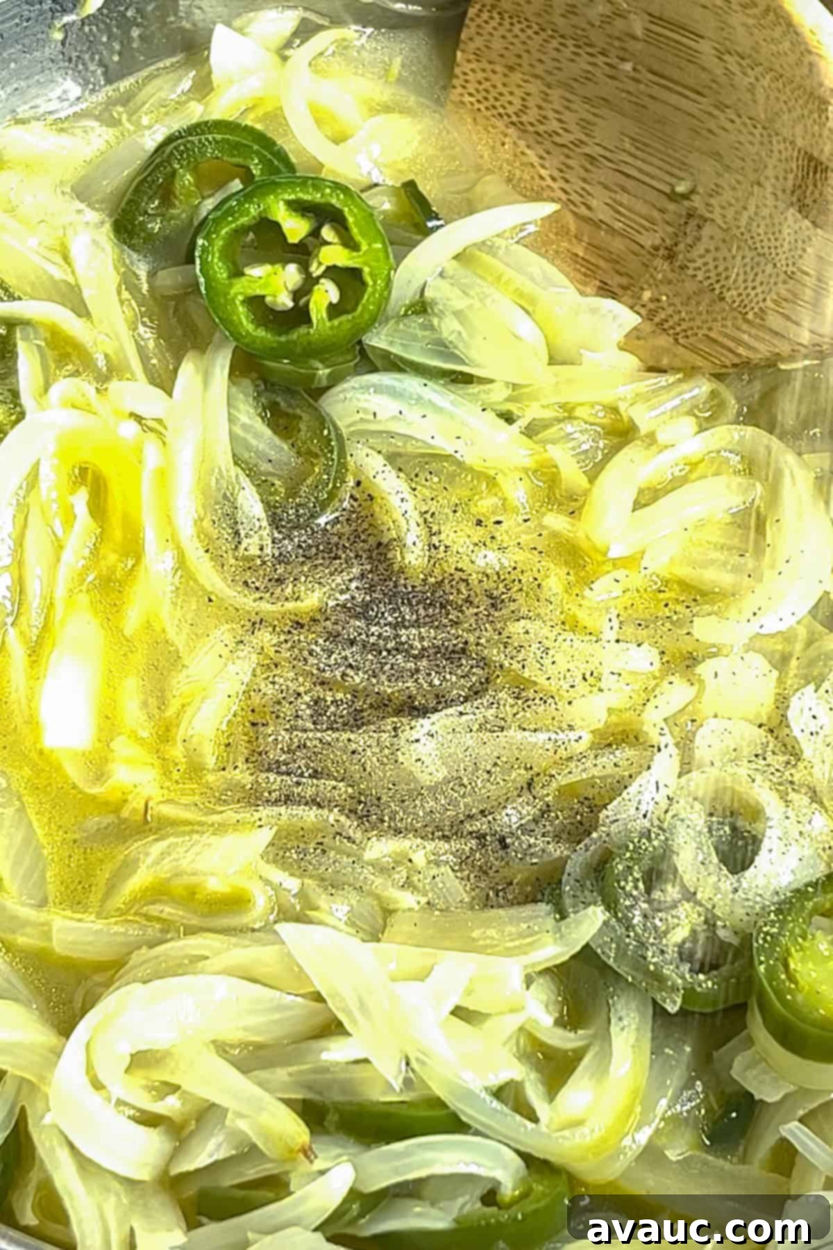 Chicken broth, sautéed aromatics, and seasoning simmering in a pot for creamy onion soup.